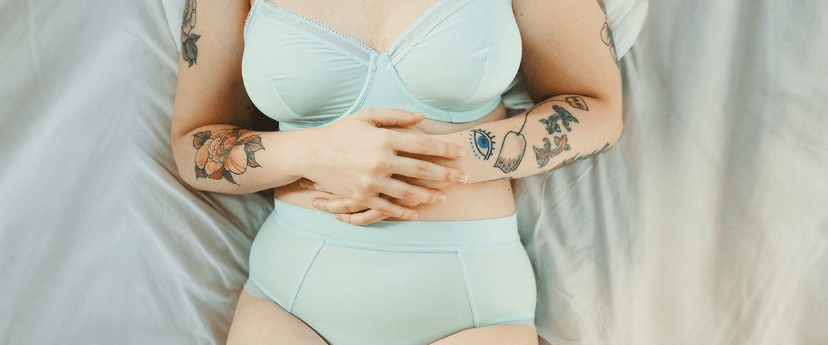 Frau in Unterwäsche hält ihren Bauch