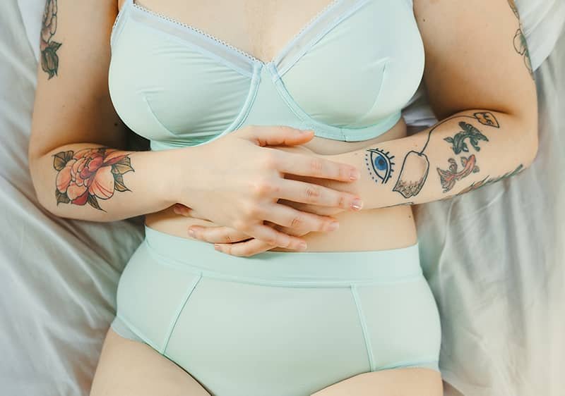 Frau in Unterwäsche hält ihren Bauch