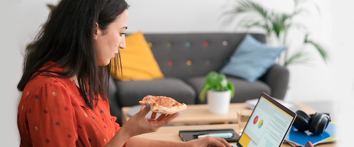 Frau isst vor ihrem Laptop