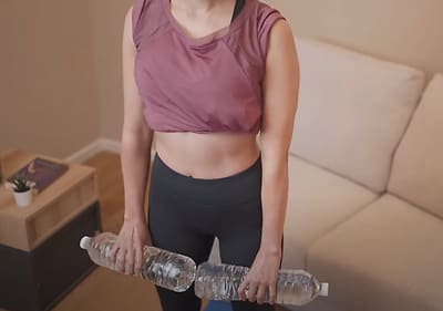 Frau trainiert mit Wasserflaschen