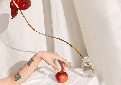Blume in Vase mit Hand und Apfel auf weißem Hintergrund
