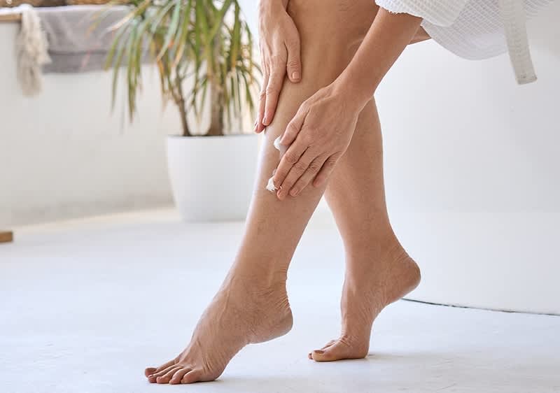 Frau cremt ihre Beine ein