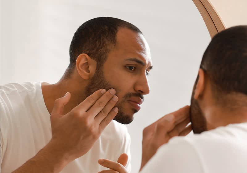 Mann pflegt Bart im Spiegel
