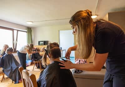 Friseurin schneidet Flüchtlingskind die Haare