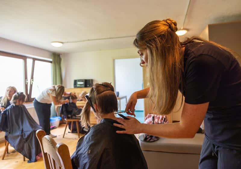 Friseurin schneidet Flüchtlingskind die Haare