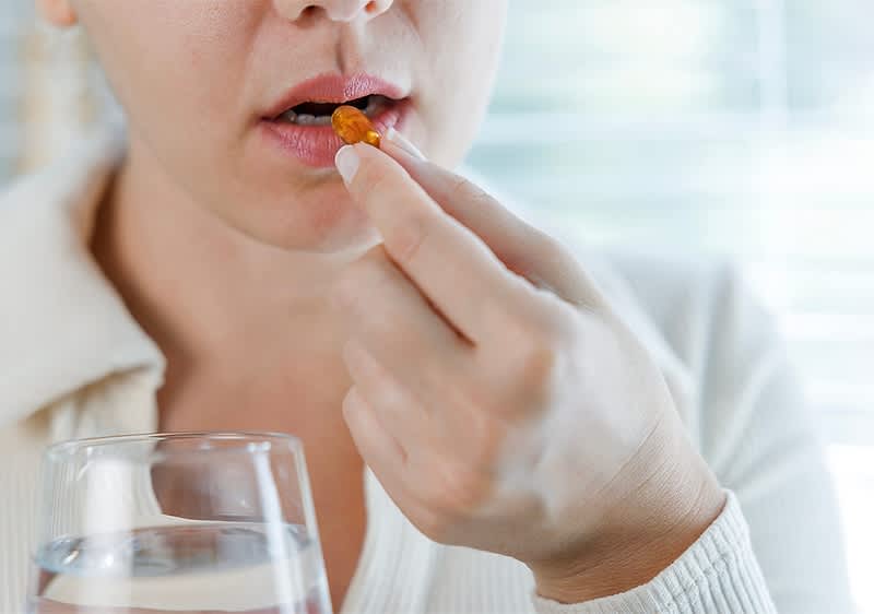 Frau nimmt Vitaminpille mit Wasserglas