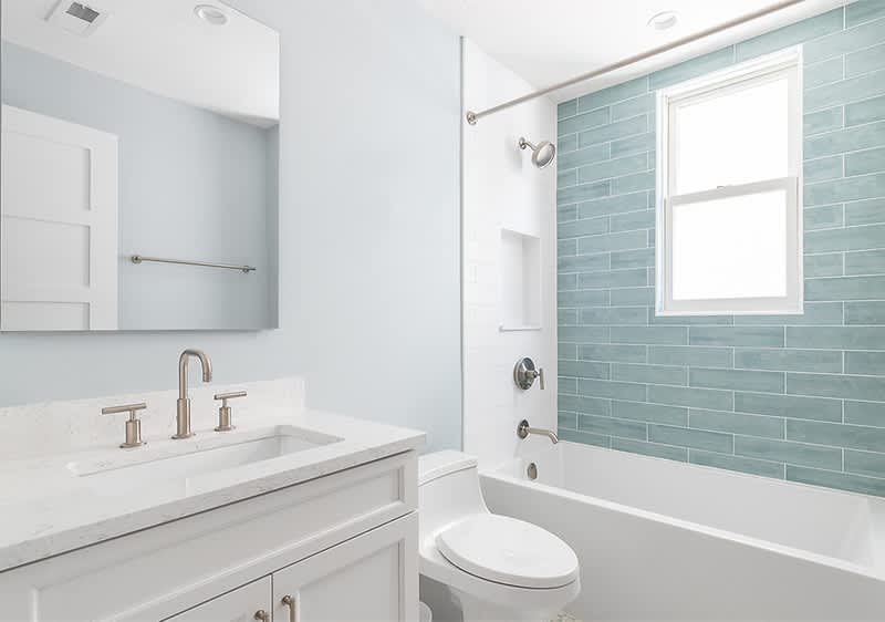 Modernes Badezimmer mit weißer Badewanne und blauen Fliesen an der Wand