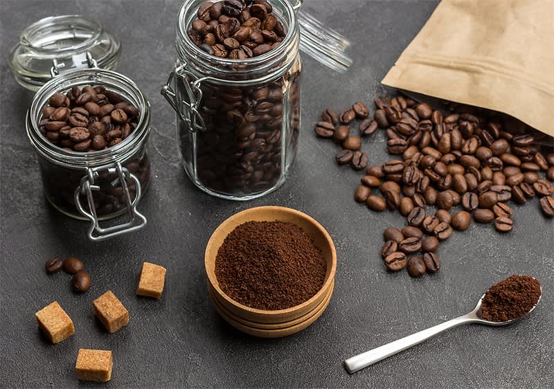 Kaffeebohnen und gemahlener Kaffee mit Zuckerwürfeln auf dunklem Hintergrund