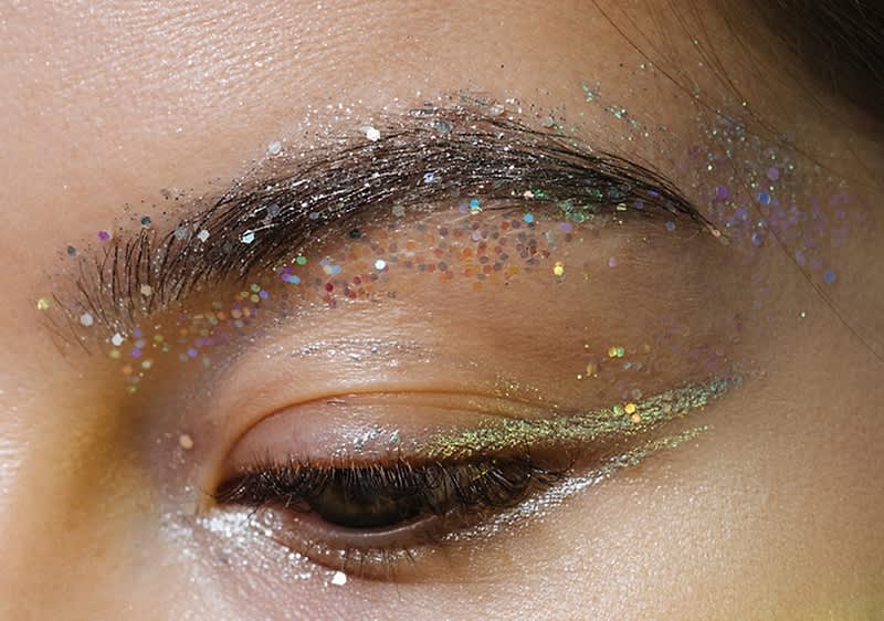 Glitzerndes Augen-Make-up mit funkelnden Partikeln und silbernem Eyeliner