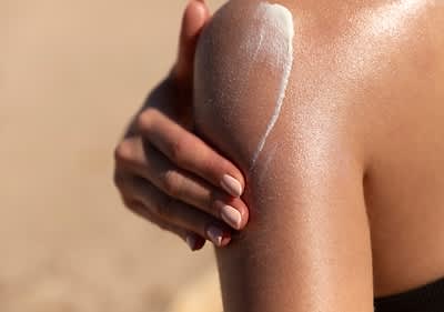Sonnencreme auf Schulter am Strand