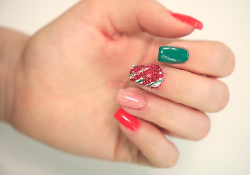 Roten Glitzer ueber lackierten Nagel streuen