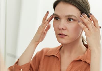 Frau mit trockener Haut vorm Spiegel