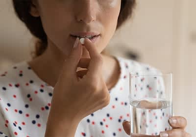 Person nimmt Tablette mit Wasserglas