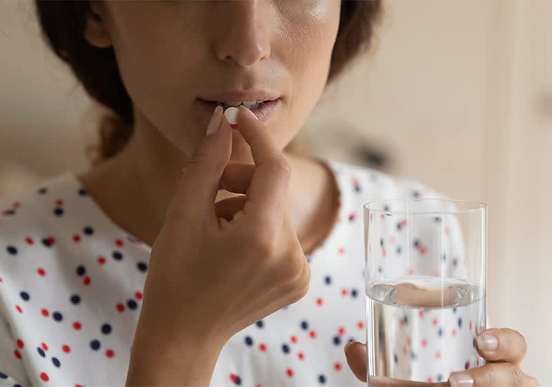 Person nimmt Tablette mit Wasserglas