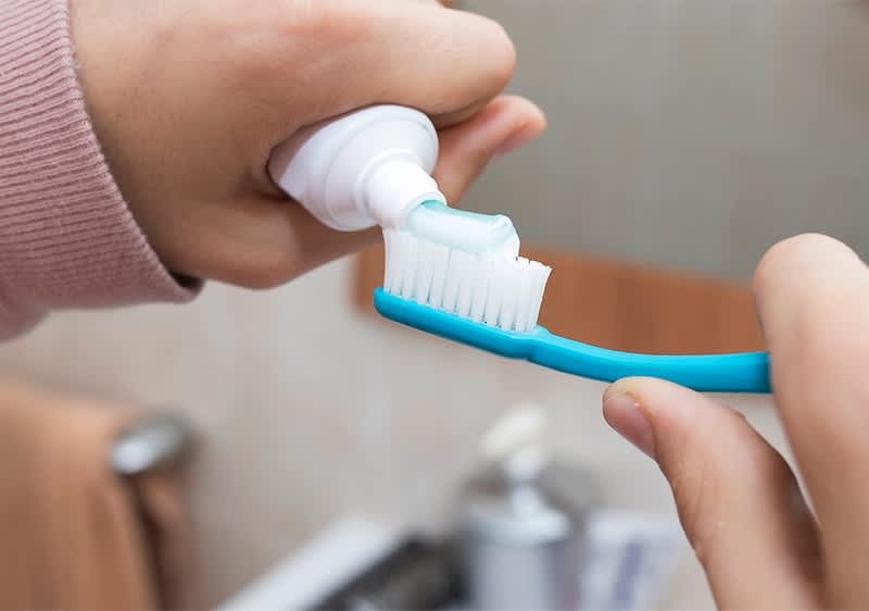 Zahnpasta auf Zahnbürste in Badezimmerumgebung