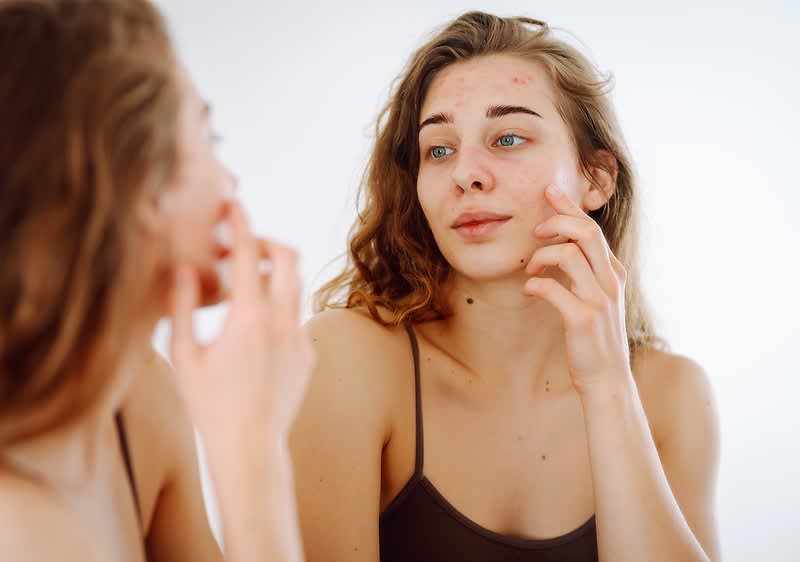 Frau betrachtet sich im Spiegel