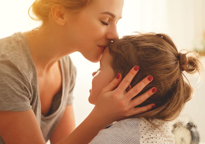 Mutter küsst Tochter auf die Stirn