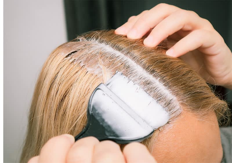 Haarfärbung am Ansatz mit Pinsel und blonden Haaren