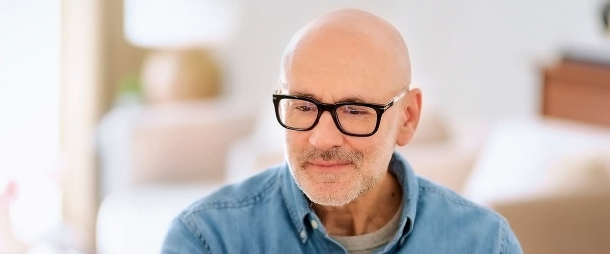 Mann mit Glatze und Brille in Freizeitkleidung