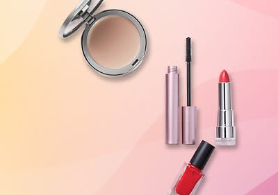 Ein Kompaktpuder, eine geöffnete Mascara, ein roter Lippenstift und ein roter Nagellack auf rosa-gelbem Hintergrund