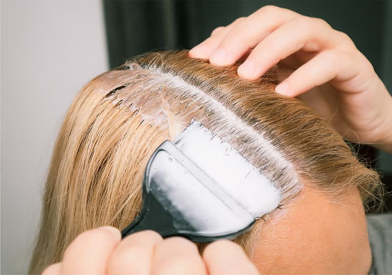 Haarfärbung am Ansatz mit Pinsel und blonden Haaren
