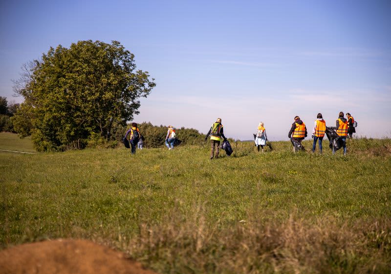 dm Mitarbeiter beim Müll sammeln auf einer grünen Wiese.