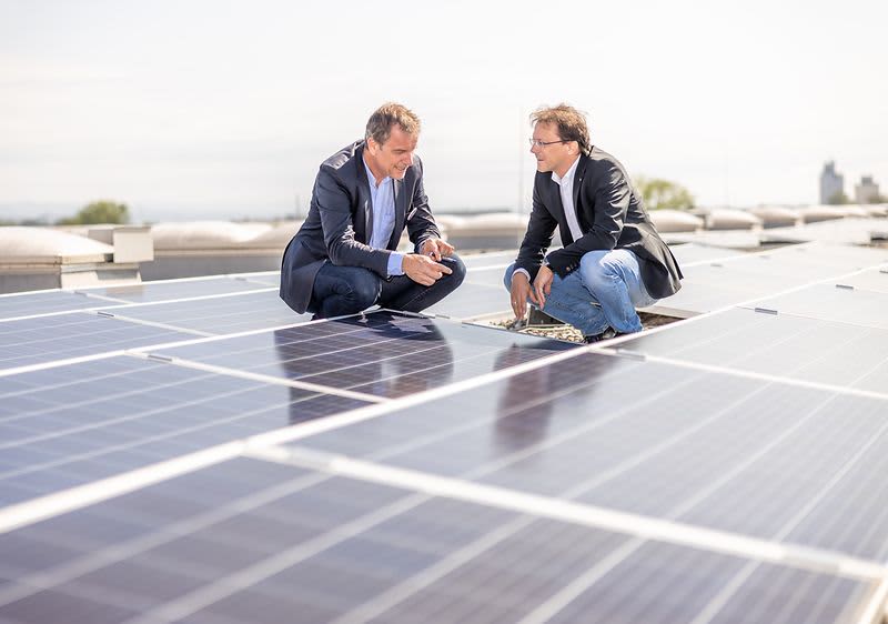 Zwei Männer befinden sich am Dach des Verteilzentrums in Enns, dessen Fläche fast komplett mit Solarzellen ausgestattet ist.