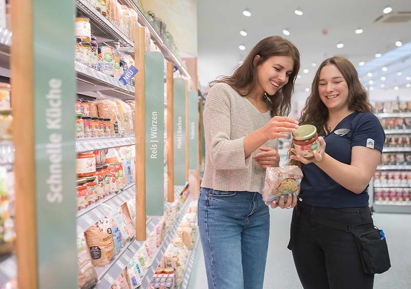 dm Mitarbeiterinnen empfangen eine Kundin an der dm friseur- und kosmetikstudio Theke
