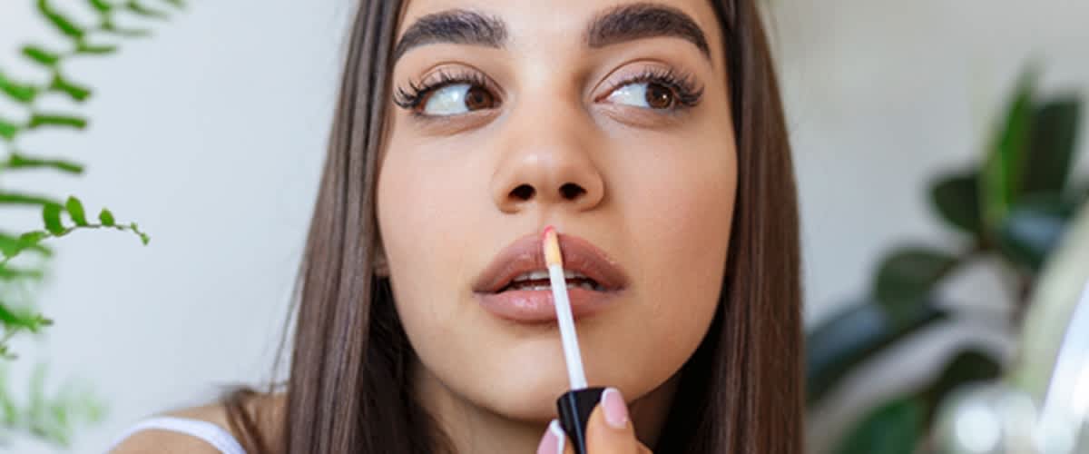 Frau trägt sich Lipgloss auf
