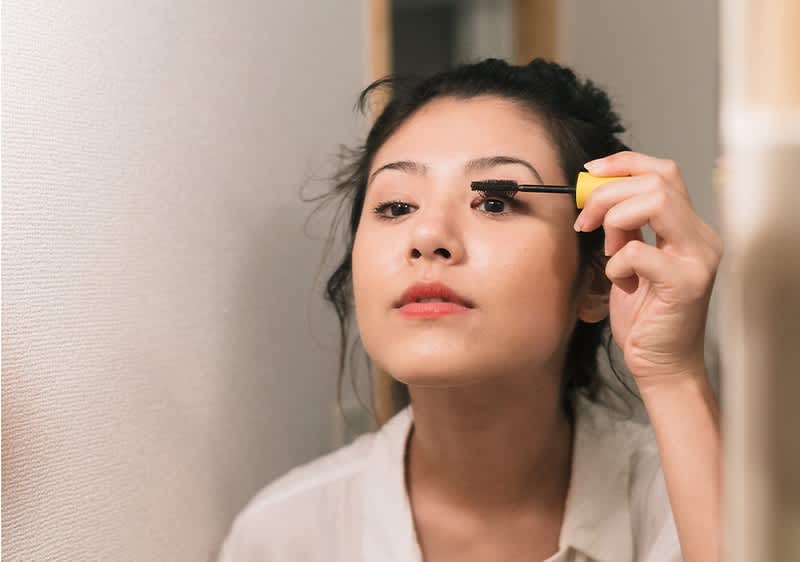 Frau schminkt Augen mit Mascara