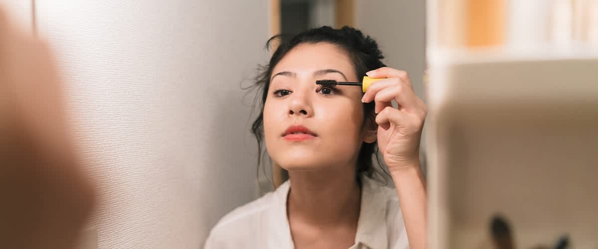 Frau schminkt Augen mit Mascara