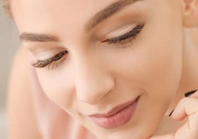 Frau mit schönen Wimpern und Wimpernzange in der Hand