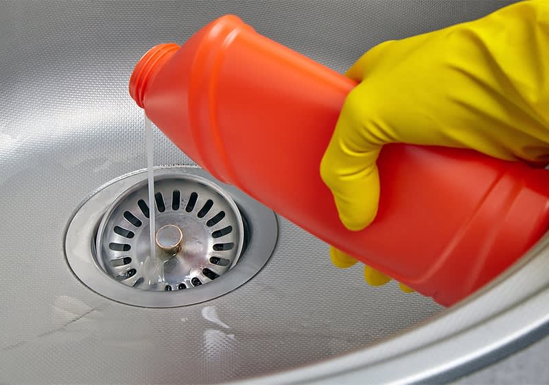 Abflussreiniger in Spüle mit gelbem Handschuh