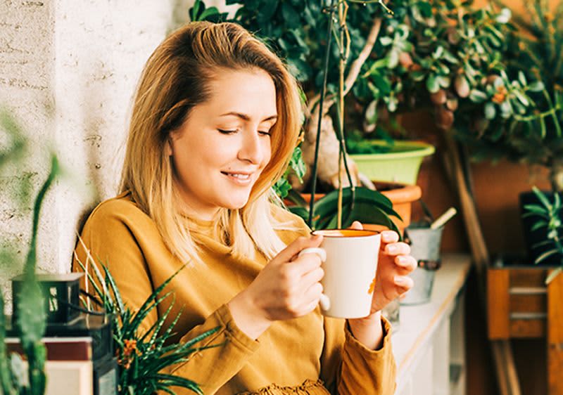Frau mit Teetasse auf Balkon