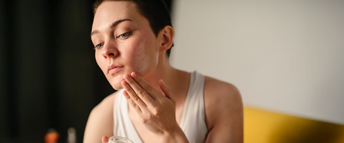 Frau mit kurzen Haaren cremt sich das Gesicht ein