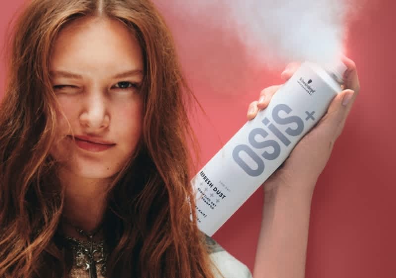 Junge Frau sprüht OSiS+ Refresh Dust Trockenshampoo auf