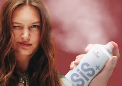 Junge Frau sprüht OSiS+ Refresh Dust Trockenshampoo auf