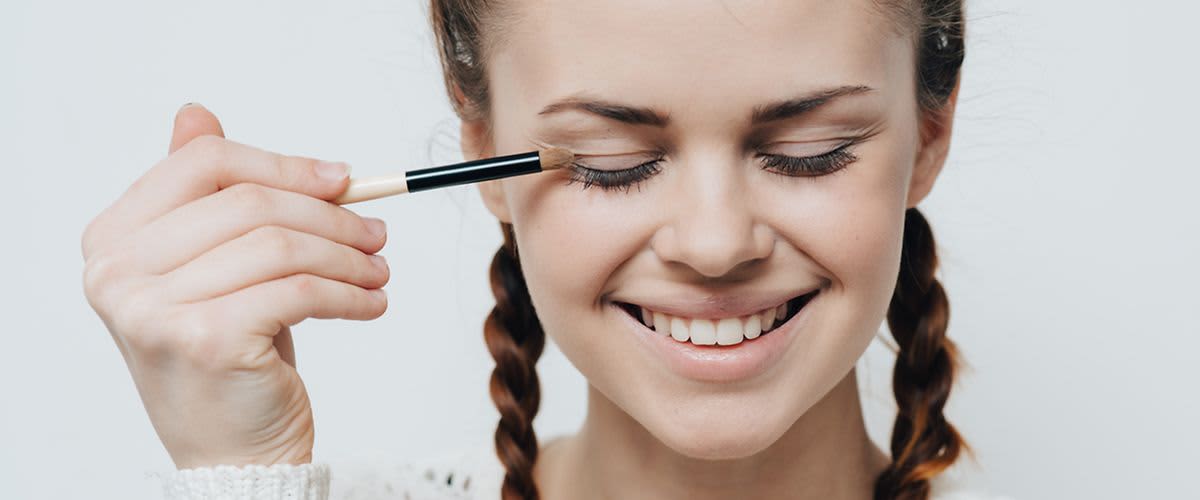 Junge Frau beim Auftragen von Lidschatten mit einem Pinsel