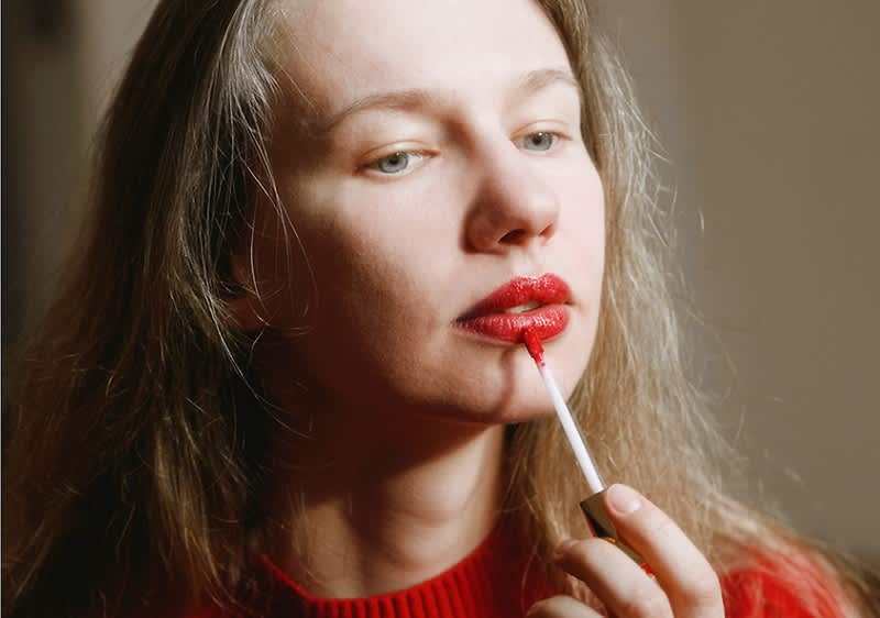 Frau schminkt rote volle Lippen