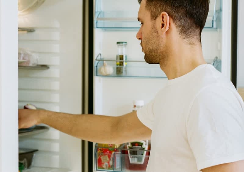 Mann holt etwas aus dem Kühlschrank