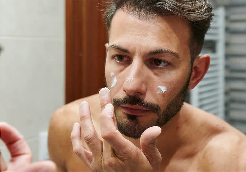 Mann der sein Gesicht pflegt