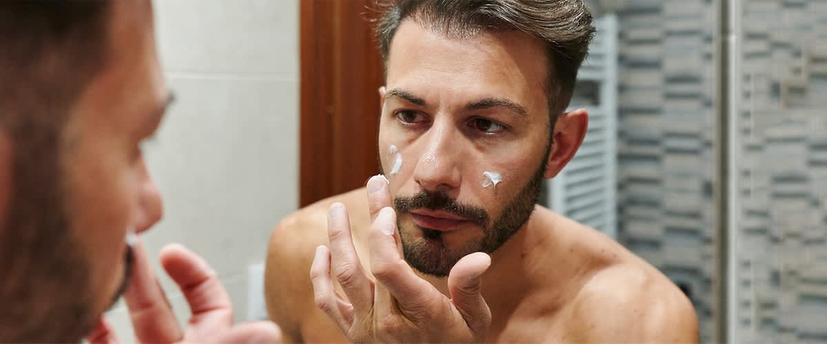 Mann der sein Gesicht pflegt