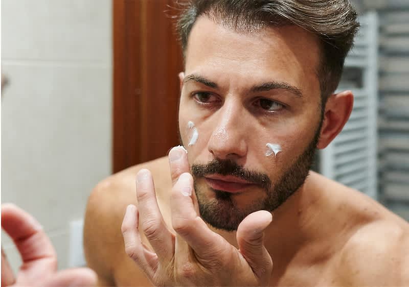 Mann der sein Gesicht pflegt