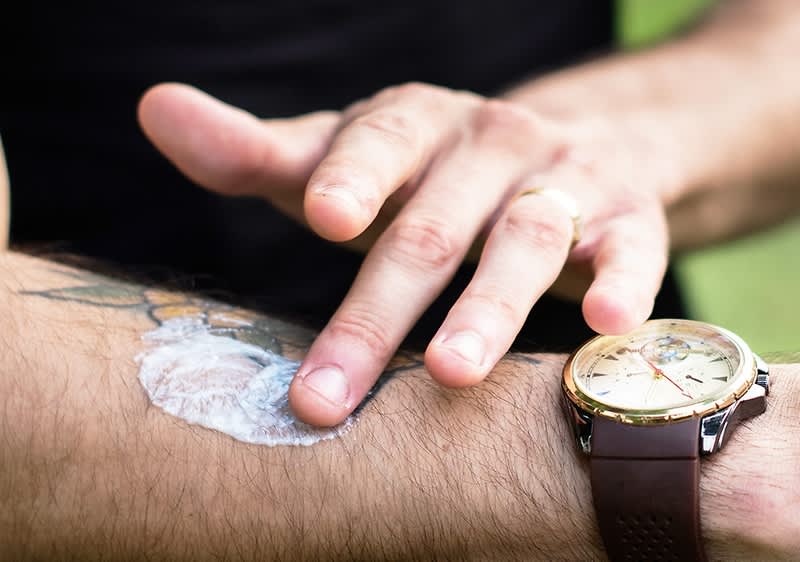 Mann schmiert sich Schutzcreme auf den Unterarm