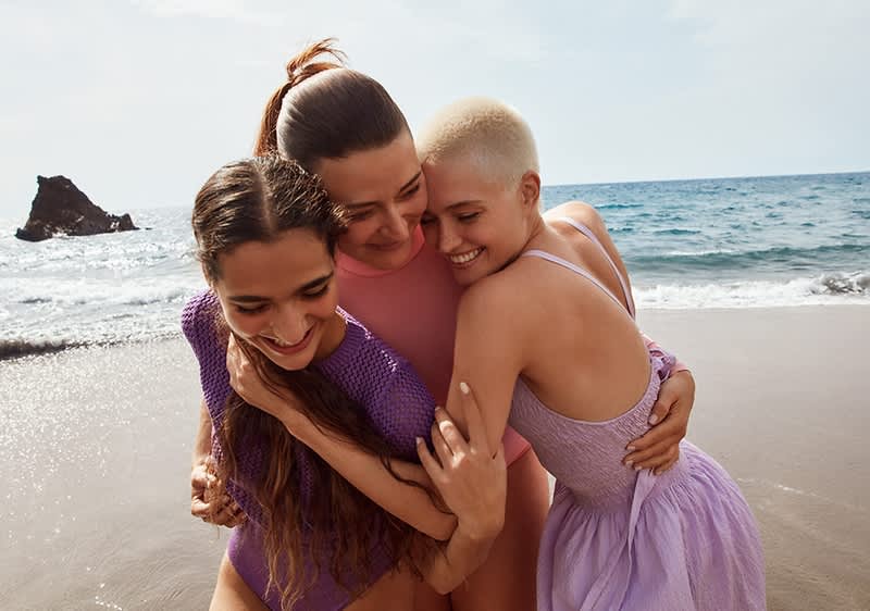 Drei Frauen, die sich umarmen am Strand