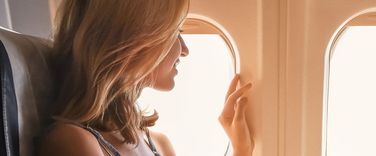 Frau blickt aus Flugzeugfenster