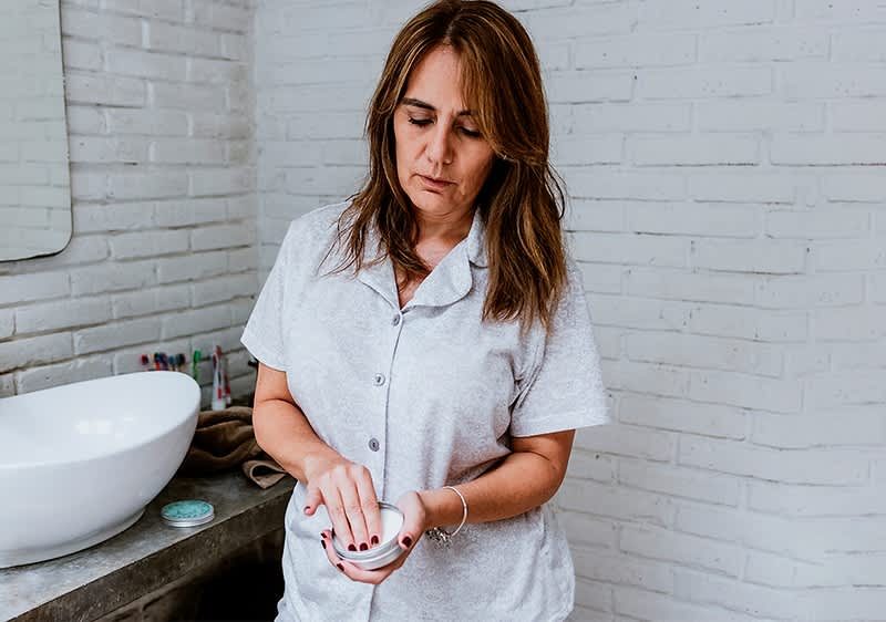 Frau im Badezimmer mit grauem Pyjama und Waschbecken
