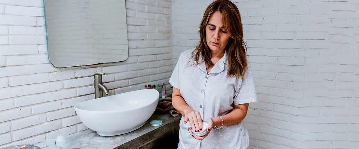 Frau im Badezimmer mit grauem Pyjama und Waschbecken