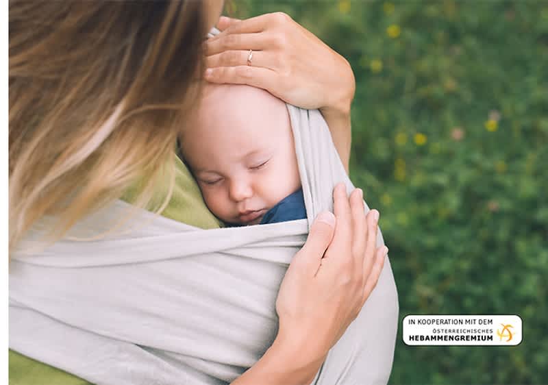 Mutter traegt Baby in Tuch