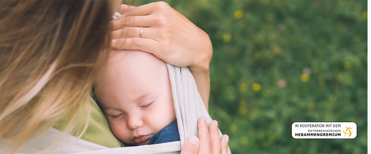 Mutter traegt Baby in Tuch